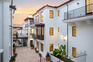 Example of a huge tuscan white three-story exterior home design in Santa Barbara with a tile roof