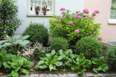 Small traditional front yard shaded garden in Munich with natural stone pavers for summer.