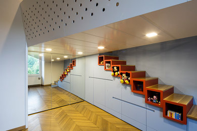 Diseño de dormitorio tipo loft moderno de tamaño medio con paredes azules, suelo de madera clara y suelo marrón