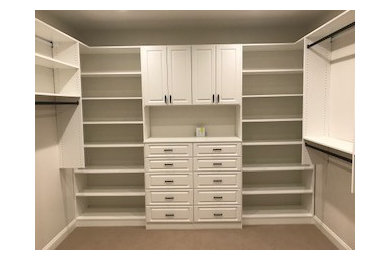 Example of a mid-sized classic gender-neutral carpeted and beige floor walk-in closet design in Other with raised-panel cabinets and white cabinets