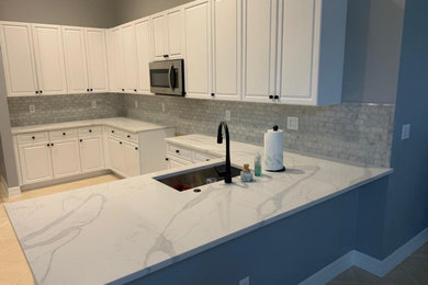 Inspiration for a mid-sized modern l-shaped ceramic tile, beige floor and vaulted ceiling eat-in kitchen remodel in Miami with a single-bowl sink, shaker cabinets, white cabinets, marble countertops, white backsplash, marble backsplash, stainless steel appliances, an island and white countertops