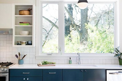 Eat-in kitchen - mid-sized farmhouse single-wall dark wood floor and brown floor eat-in kitchen idea in Austin with an undermount sink, flat-panel cabinets, white cabinets, solid surface countertops, white backsplash, porcelain backsplash, stainless steel appliances and no island