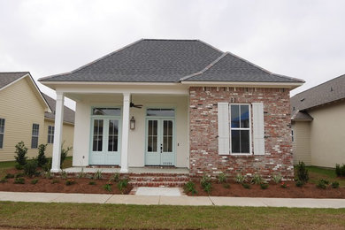 Inspiration for a mid-sized timeless white one-story brick exterior home remodel in New Orleans with a clipped gable roof