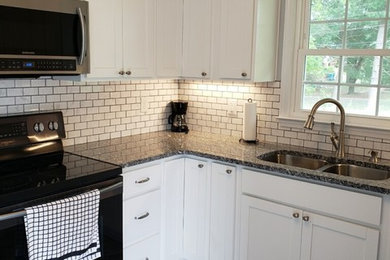 Example of a small mountain style u-shaped vinyl floor and gray floor enclosed kitchen design in Other with an undermount sink, shaker cabinets, white cabinets, granite countertops, white backsplash, subway tile backsplash, black appliances, no island and multicolored countertops