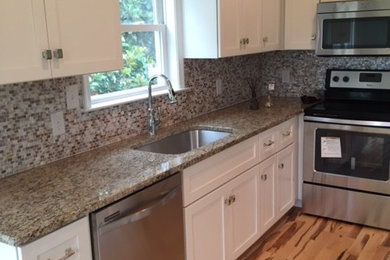 Inspiration for a coastal light wood floor kitchen remodel in Other with an undermount sink, shaker cabinets, white cabinets, granite countertops, multicolored backsplash, mosaic tile backsplash, stainless steel appliances and an island