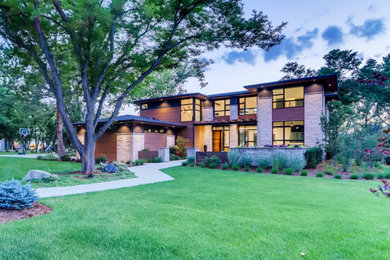 Large minimalist brown two-story stone house exterior photo in Denver with a hip roof and a shingle roof
