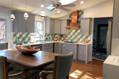 This is an example of a large transitional l-shaped eat-in kitchen in Baltimore with an undermount sink, shaker cabinets, grey cabinets, quartz benchtops, multi-coloured splashback, glass tile splashback, stainless steel appliances, medium hardwood floors, with island, brown floor and white benchtop.