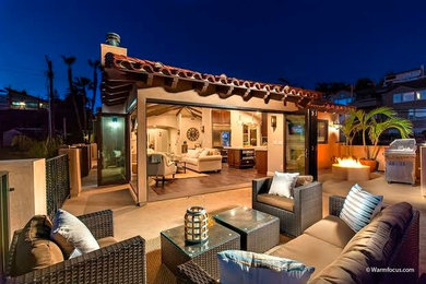 Design ideas for a mid-sized beach style backyard patio in San Diego with a fire feature, concrete slab and a roof extension.