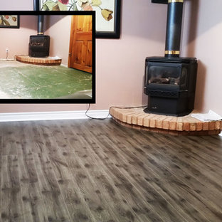 Photo of a small rustic fully buried basement in Toronto with pink walls, medium hardwood flooring, a wood burning stove and a brick fireplace surround.