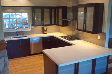 Inspiration for a contemporary u-shaped eat-in kitchen remodel in Los Angeles with an undermount sink, glass-front cabinets, brown cabinets, quartz countertops, beige backsplash, glass tile backsplash and stainless steel appliances