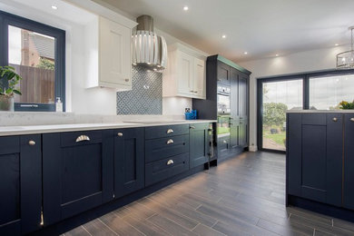 Design ideas for a mid-sized contemporary l-shaped eat-in kitchen in Other with an undermount sink, shaker cabinets, blue cabinets, quartzite benchtops, grey splashback, glass sheet splashback, stainless steel appliances, porcelain floors, a peninsula, grey floor and white benchtop.