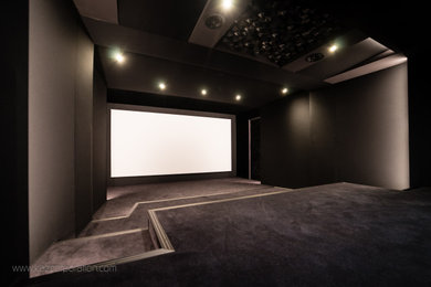 Ejemplo de cine en casa minimalista de tamaño medio con paredes negras, moqueta, pantalla de proyección y suelo negro