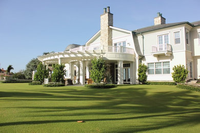 This is an example of a large coastal stone screened-in back porch design in Miami with a pergola.