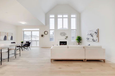 Inspiration for a contemporary open concept light wood floor, beige floor and vaulted ceiling living room remodel in Toronto with white walls