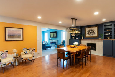 Example of a large eclectic medium tone wood floor and brown floor dining room design in Philadelphia with yellow walls, a ribbon fireplace and a tile fireplace