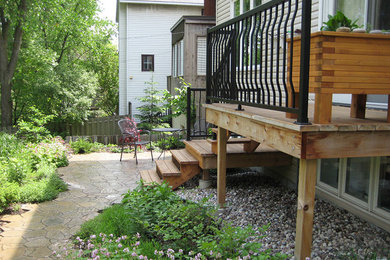 Design ideas for a mid-sized traditional full sun backyard stone landscaping in Toronto.