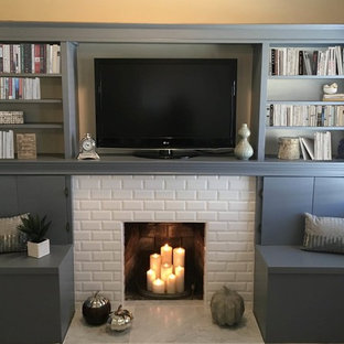 Modelo de sala de estar abierta, contemporánea, pequeña, con paredes beige, suelo de baldosas de porcelana, chimenea tradicional, marco de chimenea de baldosas y/o azulejos, pared multimedia y suelo blanco