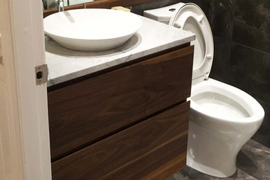 This is an example of a small contemporary 3/4 bathroom in Vancouver with flat-panel cabinets, medium wood cabinets, a two-piece toilet, brown tile, marble, brown walls, marble floors, a vessel sink, marble benchtops and brown floor.