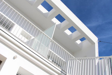 Exemple d'une grande façade de maison de ville blanche tendance en béton à un étage avec un toit plat et un toit en métal.