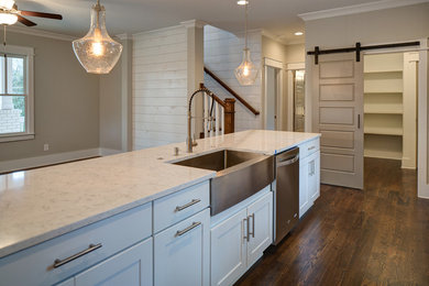 Large transitional l-shaped dark wood floor and brown floor eat-in kitchen photo in Atlanta with a farmhouse sink, recessed-panel cabinets, white cabinets, quartz countertops, brown backsplash, subway tile backsplash, stainless steel appliances and an island