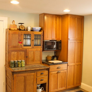 Mid-sized craftsman kitchen pantry appliance - Inspiration for a mid-sized craftsman u-shaped kitchen pantry remodel in Detroit with a farmhouse sink, shaker cabinets, medium tone wood cabinets, granite countertops, green backsplash, black appliances and no island