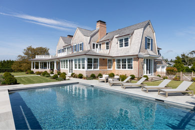 Beach style grey house exterior in New York with a gambrel roof and a shingle roof.