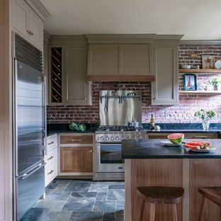 Lantlig inredning av ett mellanstort svart svart kök, med skåp i shakerstil, bruna skåp, rostfria vitvaror, en köksö, en undermonterad diskho, rött stänkskydd, stänkskydd i tegel, skiffergolv och flerfärgat golv