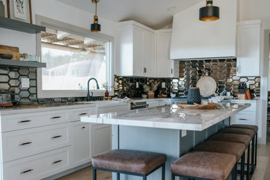 Inspiration for a mid-sized transitional u-shaped separate kitchen in San Francisco with a farmhouse sink, shaker cabinets, white cabinets, solid surface benchtops, metallic splashback, ceramic splashback, stainless steel appliances, light hardwood floors, with island, brown floor, white benchtop and vaulted.