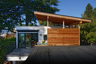 Photo of a mid-sized contemporary backyard deck in Seattle with a roof extension.