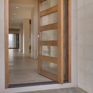 Ispirazione per una porta d'ingresso chic di medie dimensioni con pareti beige, pavimento in cemento, una porta a pivot, una porta in vetro e pavimento beige