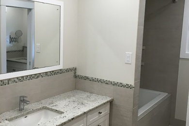 Tub/shower combo - mid-sized traditional tub/shower combo idea in Calgary with granite countertops, shaker cabinets, white cabinets, gray walls and an undermount sink