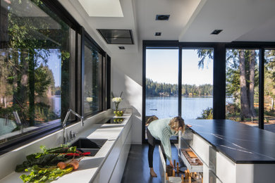 Inspiration for a large contemporary l-shaped concrete floor, gray floor and vaulted ceiling open concept kitchen remodel in Seattle with a double-bowl sink, flat-panel cabinets, gray cabinets, quartz countertops, white backsplash, quartz backsplash, stainless steel appliances, an island and white countertops