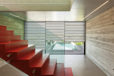Imagen de escalera suspendida moderna de tamaño medio con escalones de hormigón, contrahuellas de hormigón, barandilla de vidrio y madera