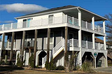 Large beach style white three-story vinyl and clapboard exterior home photo in Other with a shingle roof and a black roof