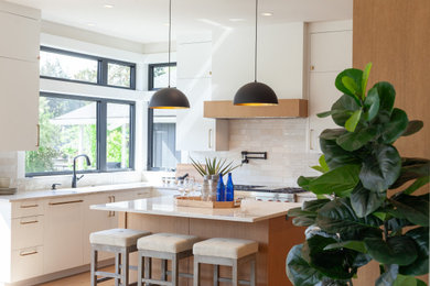 Example of a minimalist u-shaped eat-in kitchen design in Portland with flat-panel cabinets, white cabinets, paneled appliances and an island