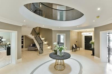 Photo of an expansive contemporary hallway in Hampshire with a single front door, white walls, limestone flooring, a grey front door and white floors.