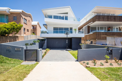 This is an example of a mid-sized contemporary three-storey glass white house exterior in Sydney with a hip roof and a metal roof.