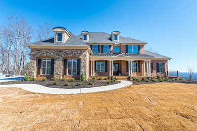 Example of a large classic two-story brick house exterior design in Atlanta with a hip roof and a shingle roof