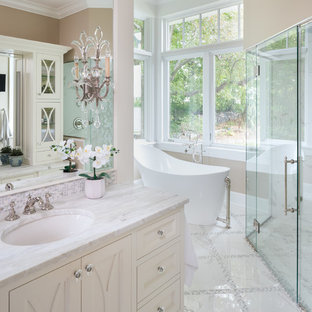 Example of a classic beige tile white floor freestanding bathtub design in Minneapolis with recessed-panel cabinets, beige cabinets, beige walls, an undermount sink and white countertops