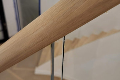 Foto de escalera curva actual grande con barandilla de madera