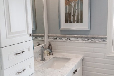 Bathroom - mid-sized transitional master gray tile, white tile and ceramic tile ceramic tile and beige floor bathroom idea in Toronto with raised-panel cabinets, white cabinets, gray walls, a drop-in sink and marble countertops