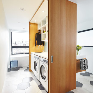 Small contemporary single-wall laundry cupboard in Toronto with flat-panel cabinets, white walls, a side by side washer and dryer and medium wood cabinets.