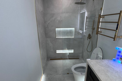 Example of a mid-sized trendy gray tile porcelain tile, gray floor and single-sink doorless shower design in Houston with shaker cabinets, black cabinets, a bidet, an undermount sink, quartz countertops, beige countertops, a niche and a built-in vanity