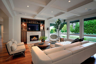 Example of a trendy open concept medium tone wood floor family room design in Vancouver with white walls, a standard fireplace and a wall-mounted tv