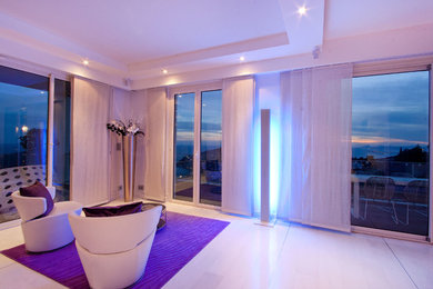 Idées déco pour un grand salon contemporain ouvert avec un mur blanc, aucune cheminée, un téléviseur encastré et un sol blanc.
