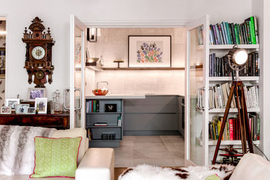 Photo of a small contemporary enclosed kitchen in London with an integrated sink, flat-panel cabinets, grey cabinets, engineered stone countertops, grey splashback, black appliances, ceramic flooring and white worktops.