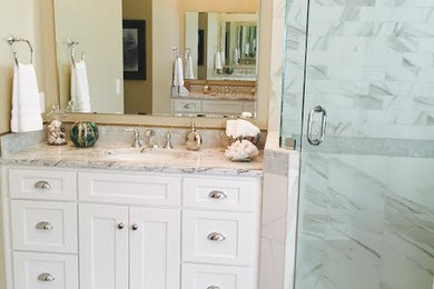 Inspiration for a mid-sized transitional master white tile and porcelain tile porcelain tile and brown floor bathroom remodel in Other with an undermount sink, recessed-panel cabinets, white cabinets, granite countertops, a one-piece toilet, beige walls and a hinged shower door
