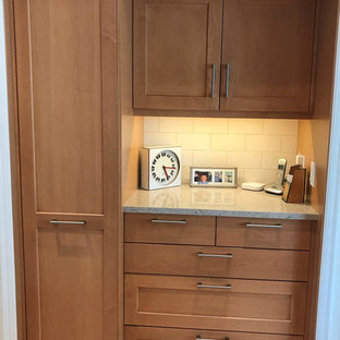 Cette image montre une arrière-cuisine craftsman en L de taille moyenne avec un évier encastré, un placard à porte shaker, des portes de placard en bois brun, un plan de travail en quartz modifié, une crédence blanche, une crédence en carreau de céramique, un électroménager en acier inoxydable, un sol en bois brun, une péninsule, un sol beige et un plan de travail blanc.