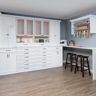 Inspiration for a modern craft room in Other with blue walls, medium hardwood flooring, a built-in desk and brown floors.
