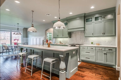 Eat-in kitchen - mid-sized craftsman medium tone wood floor and brown floor eat-in kitchen idea in Oklahoma City with a single-bowl sink, flat-panel cabinets, blue cabinets, quartz countertops, gray backsplash, ceramic backsplash, stainless steel appliances and an island